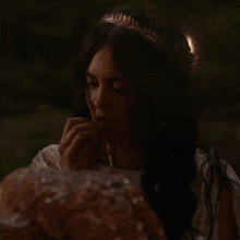 a woman with a tiara on her head looks down