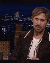 a man with a beard is wearing a black jacket and a white shirt and making a funny face .