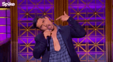 a man in a suit and plaid shirt is singing into a microphone .