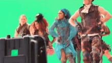 a group of people are dancing in front of a green background