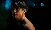 a shirtless man is standing in a dark room with a blurry background