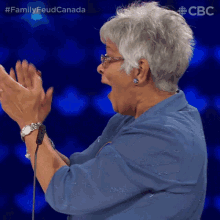 a woman applauds while wearing a watch and a blue shirt with a cbc logo behind her