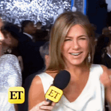 a woman is smiling while holding a microphone that says " et " on it