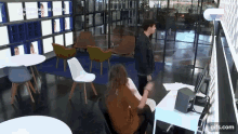 a man and a woman are standing in a room with chairs and tables ..