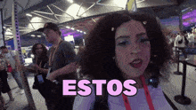 a woman with curly hair stands in front of a sign that says " estos "