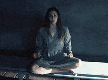 a woman in a grey dress sits on a bench with her legs crossed