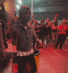 a man in a denim jacket is dancing in front of a crowd of people