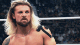 a man with long blonde hair and a beard is standing in a wrestling ring with the words the megaman on the bottom right