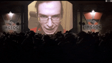 a man with glasses is smiling in front of a sign that says ingsoc