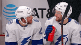 two hockey players are talking to each other while holding a red cup .