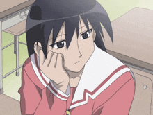 a girl sitting at a desk with her hand resting on her chin