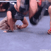 a woman is doing a handstand in a wrestling ring while another woman watches .