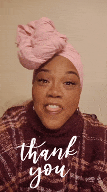 a woman wearing a pink turban and a plaid sweater says thank you