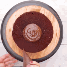 a person is spreading chocolate frosting on a cake