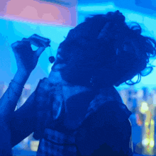 a woman singing into a microphone in a dark room with blue lights