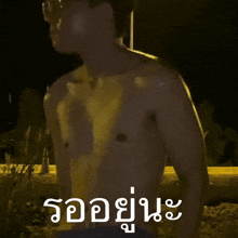 a shirtless man is standing in front of a sign that says ' รอ อยู่ นะ ' on it