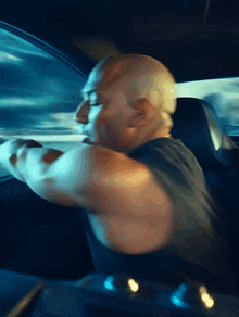 a bald man is driving a car in a blurry photo