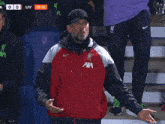a man wearing a red jacket that says ' axa ' on the front