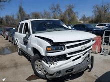 a white chevrolet suv with a damaged front end is parked in a parking lot