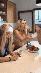 three women are sitting at a table drinking coffee
