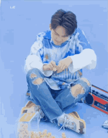 a young man is sitting on the floor with a bag of nuts and a boombox behind him