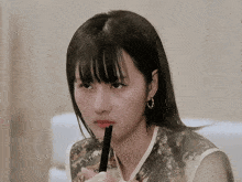 a woman with bangs is holding a chopstick to her mouth