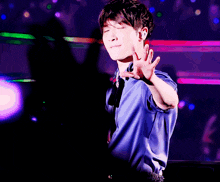 a man in a blue shirt with his eyes closed and his hands in the air