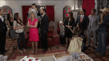 a group of people standing around a table with a cake