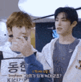 two young men are standing next to each other with one wearing a donghyeon shirt