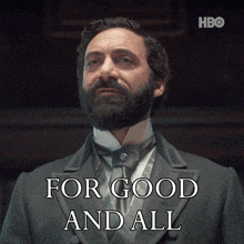 a man with a beard is standing in front of a sign that says " for good and all "