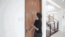 a woman in a black shirt is opening a wooden door