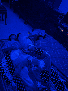 a couple laying on a bed with a blue light shining on them