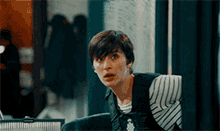 a woman with short hair is wearing a striped shirt and vest .