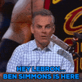 a man sitting in front of a microphone with the words hey lebron ben simmons is here below him