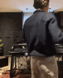 a man wearing headphones is standing in front of a desk in a room .