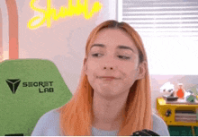 a woman with red hair is sitting in front of a green secret lab chair