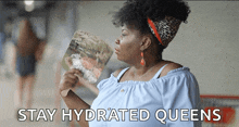 a woman holding a fan with the words stay hydrated queens written below her