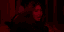 a woman with long hair is standing in a dark room with red lights .