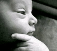 a close up of a baby 's face with a hand on his chin