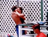 a man and a woman kissing in front of a lattice wall
