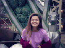 a woman wearing a purple shirt and a red sweater smiles