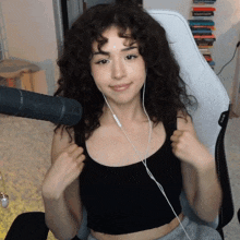 a woman with curly hair wearing headphones and a black tank top