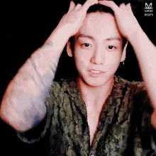 a man with a tattoo on his arm holds his hands to his head and looks at the camera