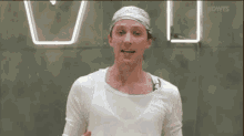 a man wearing a bandana and a white shirt stands in front of a neon sign that says dwts