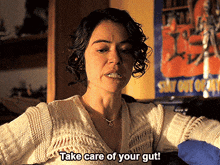 a woman says take care of your gut in front of a poster that says stay out of it