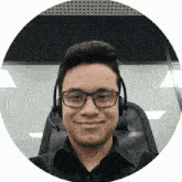 a man wearing glasses and a headset is smiling for the camera