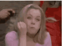 a woman in a pink shirt is making a funny face