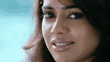 a woman with a bindi on her forehead smiles