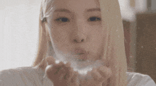 a close up of a woman blowing powder out of her hands