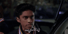 a young man is sitting in the driver 's seat of a car with a medal around his neck .